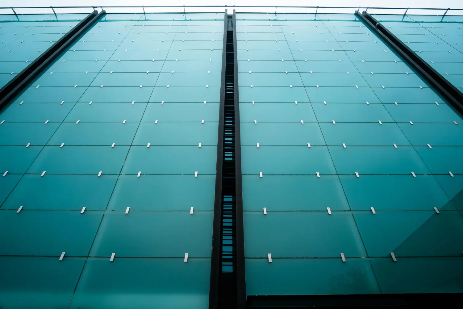 Moderne Structural Glazing Fassade an einem Bürogebäude mit spiegelnden Glaselementen.